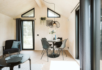 Soggiorno e sala da pranzo luminosi e moderni nella tiny house Est al Holiday park De Klepperstee, Paesi Bassi.