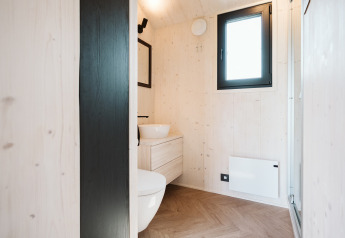 Modernes Bad in einem Tiny House im Holiday Park De Klepperstee, Niederlande, mit Holzverkleidung und Fenster.