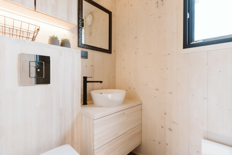 Modernes, helles Bad im Tiny House Est im Ferienpark De Klepperstee in den Niederlanden mit schwarzen Armaturen.
