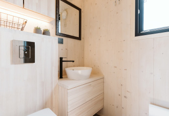 Bagno moderno e luminoso nella tiny house Est presso Holiday park De Klepperstee nei Paesi Bassi, con rubinetto nero.