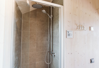Moderne douche met grijze tegels in een tiny house in vakantiepark De Klepperstee, Nederland.