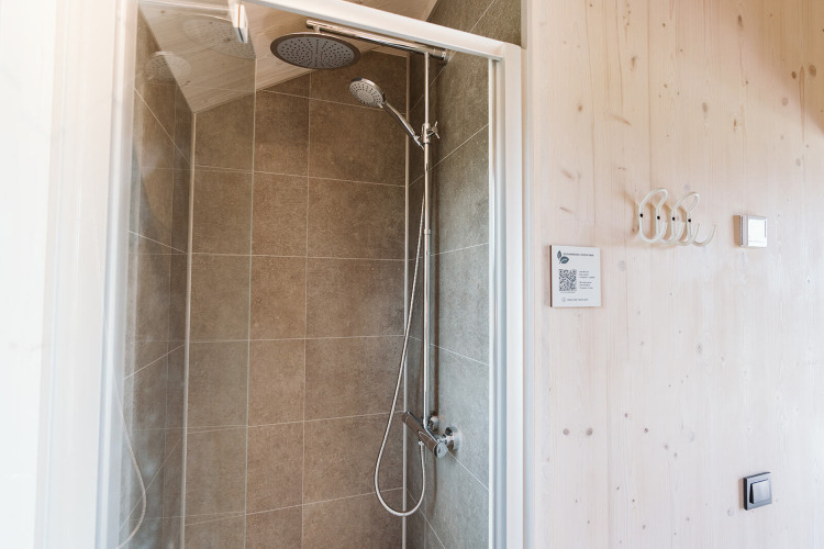 Ducha moderna con azulejos grises en una tiny house del parque de vacaciones De Klepperstee, Países Bajos.