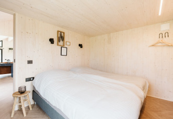 Gezellige slaapkamer met tweepersoonsbed in tiny house Est op vakantiepark De Klepperstee, Nederland.
