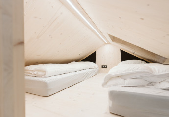 Slaapzolder met twee bedden en strakke inrichting in een tiny house in De Klepperstee, Nederland.