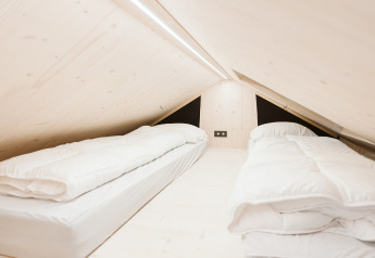 Chambre en mezzanine avec deux lits simples et bois clair dans la tiny house Est à De Klepperstee, Pays-Bas.