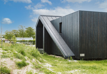 Tiny house moderna in legno nero Scandic al Holiday park De Klepperstee, immersa nel verde nei Paesi Bassi.