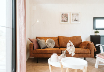 Stijlvolle woonkamer in een tiny house Scandic bij Holiday park De Klepperstee, Nederland, met bruine bank.