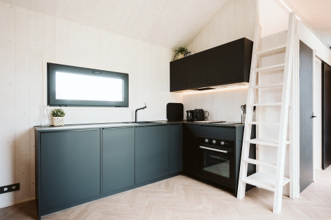 Moderne, compacte keuken in de Scandic tiny house bij Holiday park De Klepperstee in Nederland, met zwarte kasten.