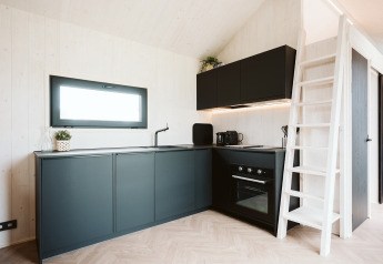 Moderne, compacte keuken in de Scandic tiny house bij Holiday park De Klepperstee in Nederland, met zwarte kasten.