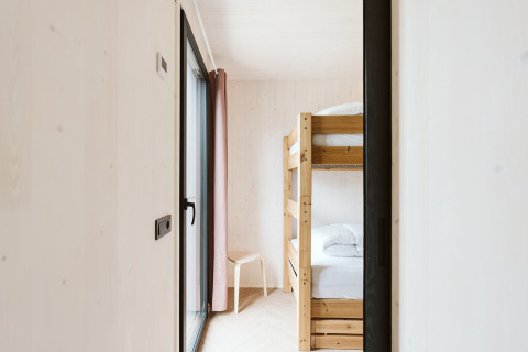 Modern, bright bedroom with bunk bed and wooden chair in the Scandic tiny house at De Klepperstee, Netherlands.