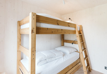 Camera luminosa e minimalista con letti a castello in legno nella tiny house Scandic a Holiday park De Klepperstee.