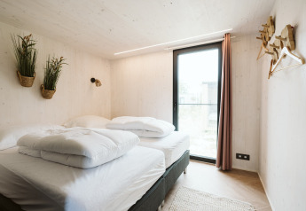 Slaapkamer in tiny house Scandic met sfeervolle inrichting op vakantiepark De Klepperstee, Nederland.