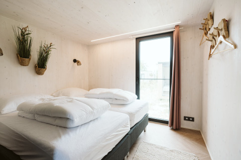 Slaapkamer in tiny house Scandic met sfeervolle inrichting op vakantiepark De Klepperstee, Nederland.