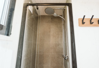 Douche moderne et compacte dans la tiny house Scandic au Holiday park De Klepperstee, Pays-Bas, carrelée.