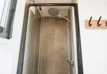Moderne compacte douche in tiny house Scandic op Holiday park De Klepperstee in Nederland met grote tegels.