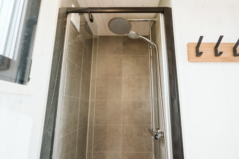 Moderne, compacte douche in tiny house Scandic op Holiday park De Klepperstee in Nederland met grote tegels.