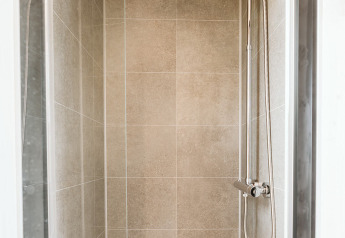 Ducha moderna con rociador de lluvia y cabezal manual en tiny house Scandic en De Klepperstee, Países Bajos.