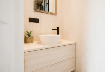 Moderne badkamerwastafel met zwarte kraan en spiegel in een tiny house bij vakantiepark De Klepperstee.