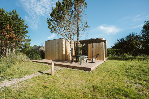 Tiny house moderna Tiny Rebel presso Holiday park De Klepperstee, Olanda, con patio in legno e ombrellone.