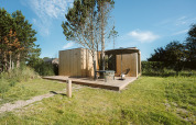 Moderne tiny house Tiny Rebel i Holiday park De Klepperstee, Holland, med træterrasse og solparasol.