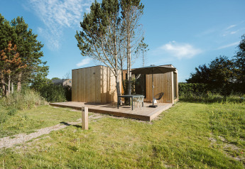 Moderna tiny house Tiny Rebel en Holiday park De Klepperstee, Países Bajos, con terraza y sombrilla.