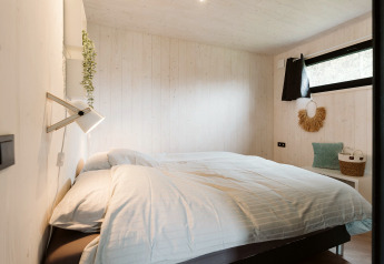 Chambre douillette dans Tiny Rebel à Holiday park De Klepperstee, Pays-Bas, avec une décoration minimaliste.