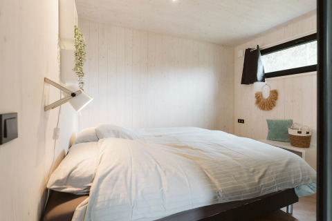 Et hyggeligt soveværelse i Tiny Rebel, en tiny house på Holiday park De Klepperstee, Holland, med skandinavisk indretning.