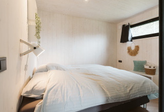 Et hyggeligt soveværelse i Tiny Rebel, en tiny house på Holiday park De Klepperstee, Holland, med skandinavisk indretning.