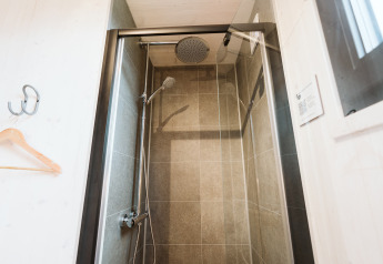Moderne douche met glazen deur in Tiny Rebel bij vakantiepark De Klepperstee in Nederland.