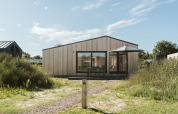 Billede af tiny house Backer i ferieparken De Klepperstee, Holland, omgivet af natur og blå himmel.