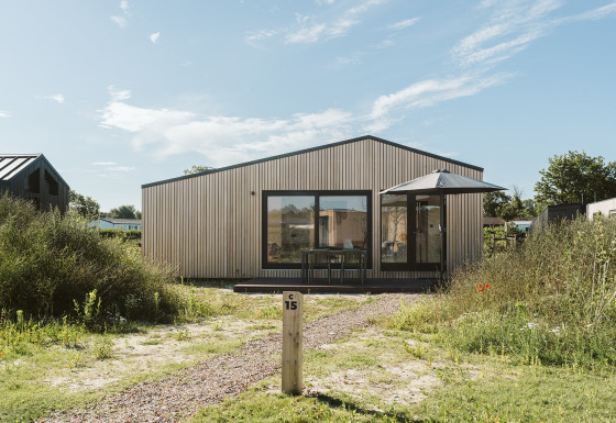 Billede af tiny house Backer i ferieparken De Klepperstee, Holland, omgivet af natur og blå himmel.