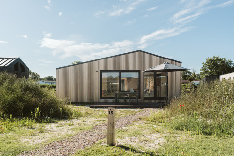 Foto van tiny house Backer op vakantiepark De Klepperstee in Nederland, omgeven door groen en zonlicht.
