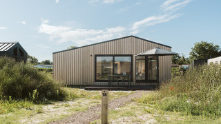 Foto van tiny house Backer op vakantiepark De Klepperstee in Nederland, omgeven door groen en zonlicht.