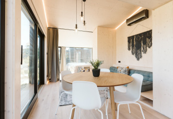 Intérieur lumineux et moderne de la tiny house Backer au Holiday park De Klepperstee, coin repas et canapé.
