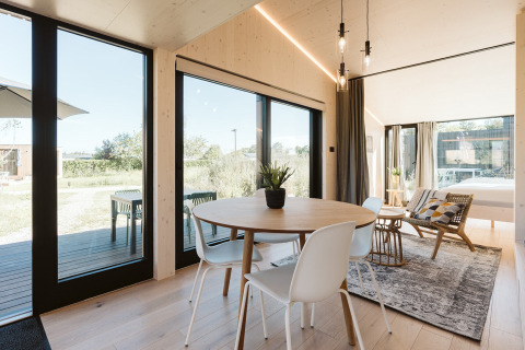 Licht en modern tiny house-interieur bij Holiday park De Klepperstee met grote ramen en uitzicht op natuur.