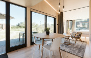 Licht en modern tiny house-interieur bij Holiday park De Klepperstee met grote ramen en uitzicht op natuur.