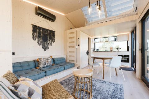 Modernes Tiny House mit heller Einrichtung, gemütlicher Sitzgruppe und Küche im Ferienpark De Klepperstee, Niederlande.