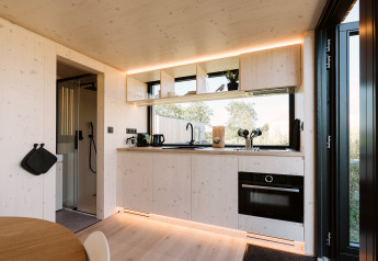 Modernes, helles Tiny-House-Küche mit großen Fenstern, Einbauofen und offenen Regalen im Backer, De Klepperstee.