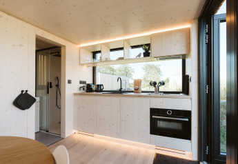 Cuisine moderne de tiny house au Backer, De Klepperstee, avec étagères ouvertes, four et grandes fenêtres.