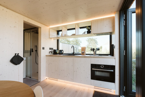 Cocina moderna de tiny house en Backer, De Klepperstee, con estantes abiertos, horno y grandes ventanales.