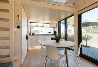 Interior luminoso y moderno de la tiny house Backer en Holiday park De Klepperstee, con área de comedor y cocina.
