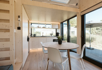 Intérieur lumineux et moderne de la tiny house Backer au Holiday park De Klepperstee, avec coin repas et cuisine.