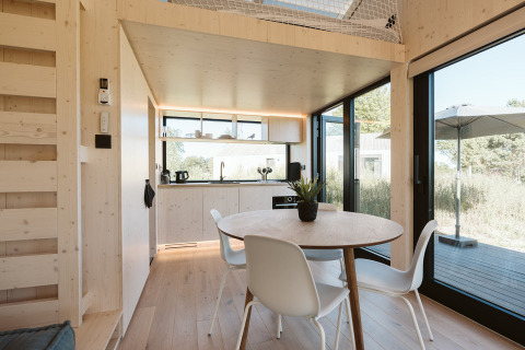 Licht, modern interieur van tiny house Backer op Holiday park De Klepperstee, met eetgedeelte en keuken.