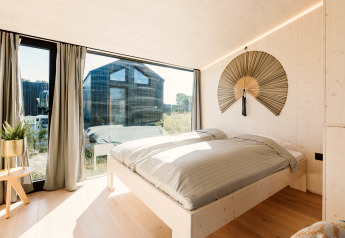 Chambre lumineuse dans la tiny house Backer au Holiday park De Klepperstee aux Pays-Bas, avec grande baie vitrée.