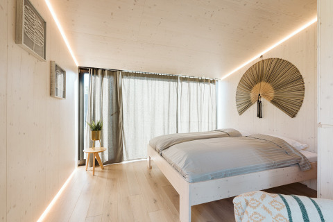 Dormitorio minimalista en la tiny house Backer del parque De Klepperstee, Países Bajos, con luz natural.