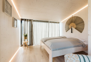 Dormitorio minimalista en la tiny house Backer del parque De Klepperstee, Países Bajos, con luz natural.