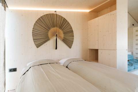 Bedroom in tiny house Backer at De Klepperstee with two single beds and a large decorative fan on the wall.