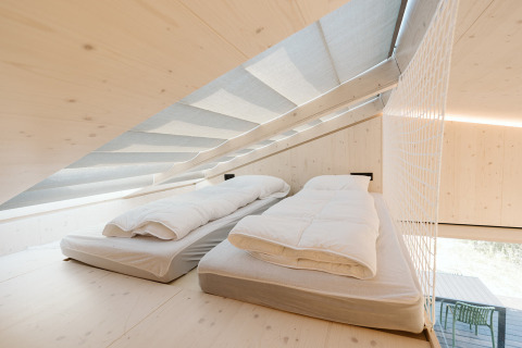 Lichte slaapzolder met twee eenpersoonsbedden in Backer tiny house bij vakantiepark De Klepperstee, Nederland.