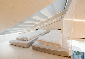 Mezzanine lumineuse avec deux lits simples dans la tiny house Backer au Holiday park De Klepperstee, Pays-Bas.