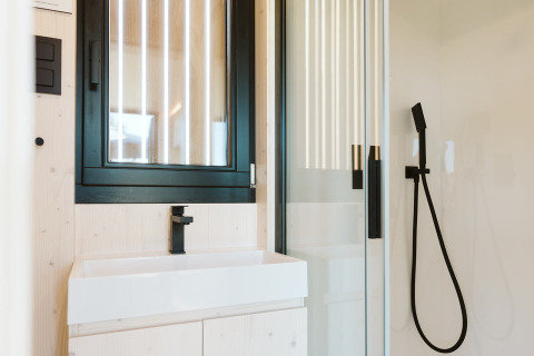 Modern compact badkamer in een tiny house bij Holiday park De Klepperstee, Nederland, met zwarte kranen.